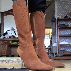 Bruna mockastövlar med stilettklack - Världens snyggaste stövlar i mocka med spetsig tå och stilettklack. De har dekorativa utskärningar och en elegant design som passar perfekt året runt.  Klackhöjd: 10cm Storlek: 38/39