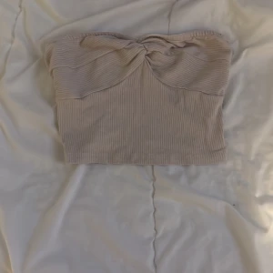 Beige ribbad tubtopp - Snygg beige ribbad tubtopp med en knutdetalj framtill. Perfekt för sommardagar eller att styla med en kavaj för en chic look.