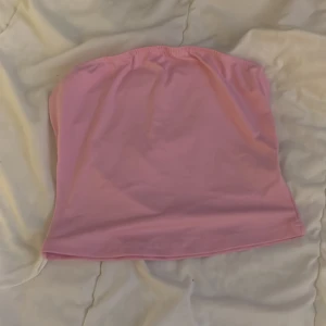 Rosa tubtopp - Säljer en söt rosa tubtopp perfekt för sommardagar. Toppen är ärmlös och har en enkel design som gör den lätt att matcha med olika outfits.
