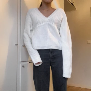 Vit stickad tröja med v-ringning bak och fram - Stilren vit stickad tröja. Den har v-ringning både bak och fram. Tröjan är något lång i ärmarna (jag är 157 cm lång). Från NLY Trend.