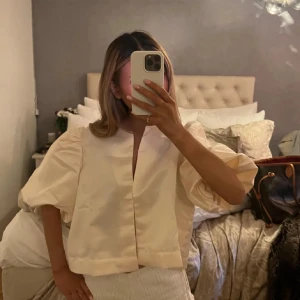 Beige blus med puffärmar - Säljer en stilren beige blus med puffiga kortärmar och en enkel design. Perfekt för en elegant look. Liknar By Malina toppen som är populär! Använd fåtal gånger💓