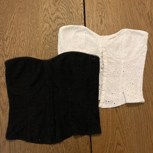 Svart och vit axelbandslös korsett - Två snygga axelbandslösa korsetter i svart och vit med broderade detaljer. Perfekta för att skapa en stilren look. De har en elegant passform och är tillverkade i ett bekvämt material.