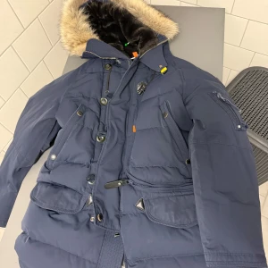 Mörkblå dunjacka från Parajumpers - Säljer en mörkblå dunjacka från Parajumpers med pälsfodrad huva och flera praktiska fickor. Jackan har både dragkedja och knappar framtill. Perfekt för kalla vinterdagar. Perfekt skick utan skador. Kemtvättad nyligen, köpt på Miinto för ett år sedan. Nypris: ca 12 000 kr  Hör av dig vid intresse! Priset är inte hugget i sten. 