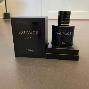 Sauvage Elixir från Dior - Säljer en flaska Sauvage Elixir från Dior. Parfymen kommer i en elegant svart flaska med en stilren design. Förpackningen är också svart och matchar flaskans exklusiva utseende. Perfekt för den som söker en lyxig doftupplevelse.