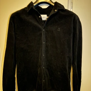 Svart manchester overshirt från Les Deux - Snygg svart overshirt från Les Deux i manchester med broderad logga på bröstet. Skjortan har långa ärmar och knappar.                                                                          Ny pris runt: 2500 kr storlek L men passar också M då den är lite liten i storlek. Perfekt som overshirt istället för jacka.            Den går inte och få tag på längre.                      Vid snabb affär kan priset diskuteras 