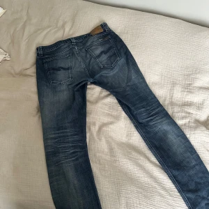 Nudie Jeans - Nudie jeans med sjukt snygg tvätt. Storlek 33/32 men sitter som 32/32. Modellen är Grim Tim dock har modell lappen tvättas ut efter 3:e tvätten. Det är lite slitet vid grenen som man kan se på sista bilden. Märks inte vid användning. Lägre pris vid snabb affär 🏬.