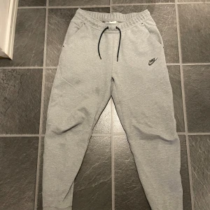 Grå tech fleece byxor från Nike - Säljer ett par grå mjukisbyxor från Nike. Byxorna är perfekta för en bekväm stil och är väldigt sköna att använda. Köpta för lite mer än ett år sedan för 1100kr, väldigt bra skick.