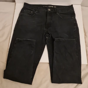 Svarta jeans från Lauren Denim - Säljer ett par svarta jeans från Lauren Denim i storlek 42 (Slim fit). De är i en klassisk stil med fem fickor och knappgylf. Jeansen har en mörk tvätt och är perfekta för både vardag och fest. De är tillverkade i ett hållbart denim-material. 
