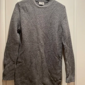 Grå stickad tröja från Acne Studios - Säljer en superfin grå stickad tröja från Acne Studios. Den är i 100% ull vilket gör den perfekt för kyliga dagar. Tröjan har en klassisk design med långa ärmar och rund hals. Perfekt för både vardag och lite mer uppklädda tillfällen. Passar perfekt till höst- och vintergarderoben!