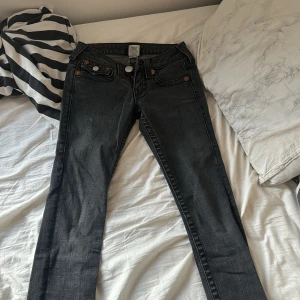 Svarta jeans från True Religion - Säljer ett par snygga svarta jeans från True Religion. De har en klassisk femficksdesign med coola detaljer på bakfickorna. Jeansen är i bra skick och perfekta för både vardag och fest. Passar till allt!