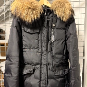 Hollies Livigno 42 - Dunjacka från Hollies, modell Livigno, i storlek 42. Jackan är i mycket bra skick då ej använd så mycket då den tyvärr är för liten för mig. Jackan sitter superfint och är riktig varm under vintern.   Material: 80% dun, 20% fjädrar. Övrigt polyester