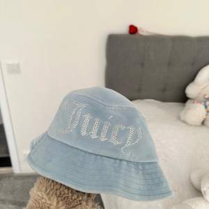 Säljer en superfin ljusblå bucket hat från Juicy Couture. Den har ett glittrigt 'Juicy' tryck på framsidan som verkligen poppar! Perfekt för sommardagar när du vill skydda dig från solen men ändå se stylish ut. Hatten är i bra skick, köpte för 699kr 