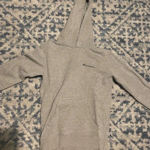 Grå champion hoodie - Jag säljer en grå champion hoodie då den är för liten för mig. Säljs i storlek Small, använd några gånger och saknar snören. En väldigt bekväm hoodie om jag ska vara ärlig. Köptes för 849kr