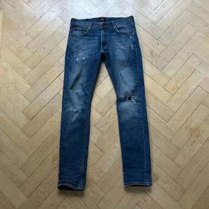 Säljer ett par snygga blå jeans från Lee. De har en klassisk femficksdesign och är i en normal passform. Jeansen är i bra skick