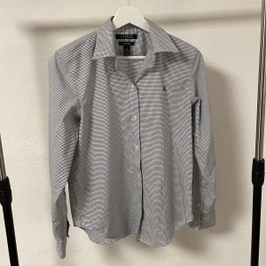  Ralph Lauren skjorta - Snygg rutig skjorta från Ralph Lauren. Skjortan är långärmad och tillverkad i 100% bomull med en non-iron finish. Perfekt för en stilren look.