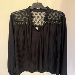 Blus med detaljer - Säljer min svarta blus med guld detaljer då den inte kommer till användning. Den här snören som man kan knyta för en elegant stil.