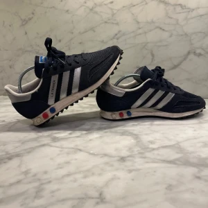 Mörkblå adidas trainers - Snygga svarta Adidas sneakers med vita ränder och detaljer. Skorna har en klassisk design med snörning och en bekväm passform. Perfekta för en liten bra detalj. Priset kan diskuteras 