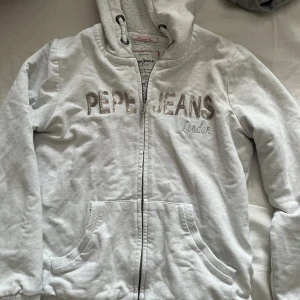 Vit hoodie från Pepe Jeans - Säljer en vit hoodie från Pepe Jeans som är väldigt varm å skön. Den har ett mjukt foder inuti och har lite kortare armar. Det står att den är i storlek S men jag skulle säga xs💕 Skriv om frågor💕💕