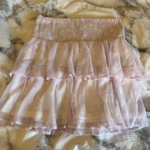 Ljuslila volangkjol - Söt ljuslila kjol med volanger och elastisk midja. Perfekt till sommaren med sitt luftiga och lätta material. Kjolen har en kort längd och ger en lekfull känsla.