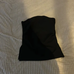 Svart tubtopp - Snygg svart tubtopp i ett mjukt och stretchigt material. Perfekt för en stilren look. Enkel att matcha med olika outfits.