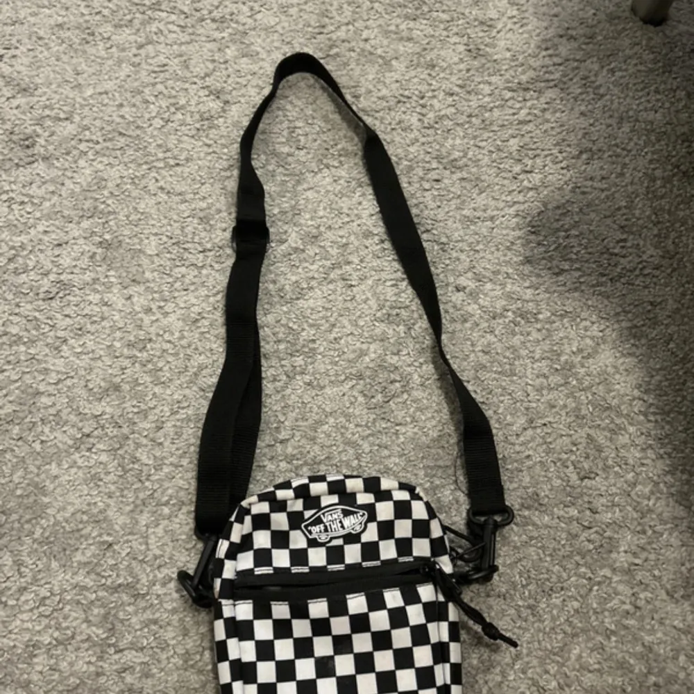 Säljer en cool svartvit rutig axelväska från Vans med det klassiska 'Off The Wall'-märket. Väskan har en justerbar axelrem och en praktisk dragkedja för säker förvaring. Perfekt för att bära med sig det viktigaste på språng.. Laukut & Käsilaukut.