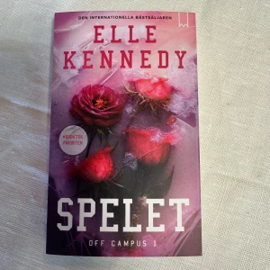 Spelet - OFF CAMPUS BOK 1 - Boken 'Spelet' av Elle Kennedy är den första delen i Off Campus-serien. Den är en internationell bästsäljare och populär på TikTok. Omslaget pryds av rosor i rosa och rött mot en isliknande bakgrund. Perfekt för dig som gillar romantik och drama.