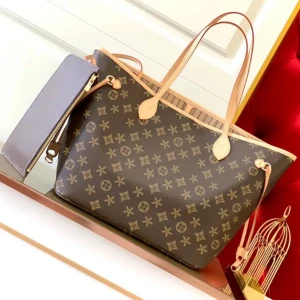 Brun mönstrad handväska med tillhörande plånbok - Snygg brun handväska med klassiskt monogrammönster och matchande plånbok. Väskan har ljusa handtag och en praktisk dragkedja. Perfekt för att bära med sig det viktigaste med stil.