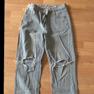 Ljusblå jeans med slitningar - Snygga ljusblå High waist  jeans med slitningar på knäna. De har en klassisk femficksdesign och en bekväm passform. Perfekta för en avslappnad stil.