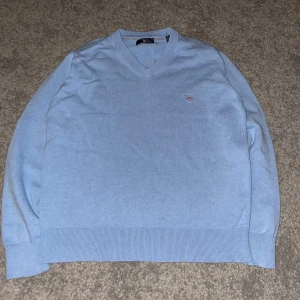 Ljusblå tröja från Gant - Säljer en stilren ljusblå tröja från Gant med v-ringning. Tröjan har långa ärmar och ribbade muddar vid ärmslut och nederkant. Perfekt för en klassisk look tröjan är storlek 146/152 11-12 år hör av er vid minsta fundering 