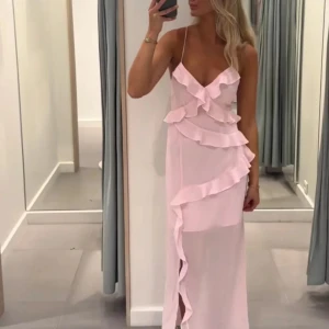 Ljusrosa långklänning med volanger - (Lånade bilder från tidigare ägare) Säljer denna jättefina ljusrosa långklänning med volanger och smala axelband från vero moda i storlek xs💗💗Klänningen har en öppen rygg med knytning, vilket ger en romantisk touch. Perfekt för somriga tillfällen.🩷 Har aldrig testat eller använt klänningen eftersom jag råkade köpa i fel storlek! Enligt tidigare ägare ska den inte ha några defekter eller liknande🩷🩷