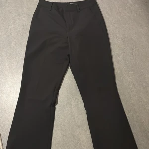 Svarta kostymbyxor från BikBok - Snygga svarta kostymbyxor från BikBok i storlek 36. Byxorna har en klassisk design med raka ben och hällor för bälte. Perfekta för en stilren look.