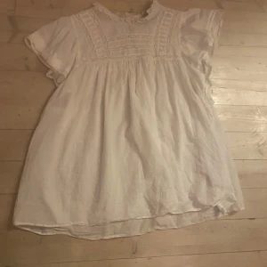 Vit blus från & Other Stories - Charmig vit blus från & Other Stories med korta ärmar och fina spetsdetaljer vid halsen. Perfekt för en somrig look med sin luftiga design och mjuka bomullsmaterial. Enkelt att matcha med både jeans och kjol.