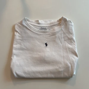 Vit t-shirt från Ralph Lauren - Säljer en klassisk vit t-shirt från Ralph Lauren med  logotypen på bröstet. Perfekt basplagg för alla tillfällen. Tillverkad i mjuk bomull för extra komfort.