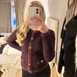 Vinröd stickad kofta med knappar - Säljer en vinröd stickad kofta med guldknappar och två fickor framtill. Bra skick! 