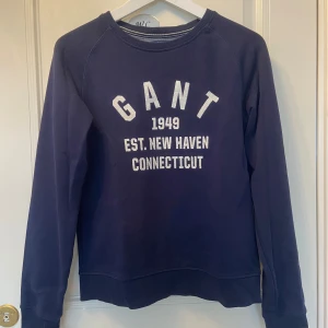 Mörkblå sweatshirt från GANT - Säljer en mörkblå sweatshirt från GANT som endast har kommit till användning ett par gånger. Passar både tjejer och killar. Köpt från kidsbrandstore i storlek 170 men passar mig som bär xs.