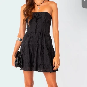 Svart axelbandslös klänning - Snygg svart axelbandslös klänning med broderade detaljer. Från märket Edikted. Aldrig använt nypris 1400