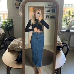 Jeanskjol med slits - Säljer en snygg jeanskjol i klassisk blå denim. Kjolen är lång och har en cool slits på sidan som ger den en extra edge. Perfekt för både vardag och fest! 🖤