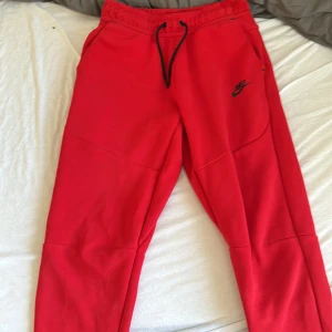 Röda Nike tech byxor - Säljer ett par röda fina nike tech byxor som är köpa i JD förra hösten 10/10 skick användes 3 ele 4 gånger förra vintern säljer pga för små öppen för byten i storlek M eller S pris (pris kan diskuteras vid snabb affär)
