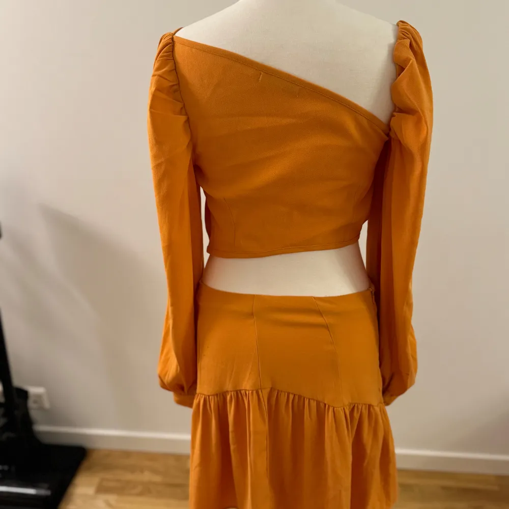 Säljer en superfin orange oneshoulder klänning från NA-KD. Den har långa ärmar och en snygg volangdetalj på kjolen. Perfekt för en sommarfest eller en utekväll! Klänningen är i nyskick och har en tight passform som framhäver figuren.. Klänningar.