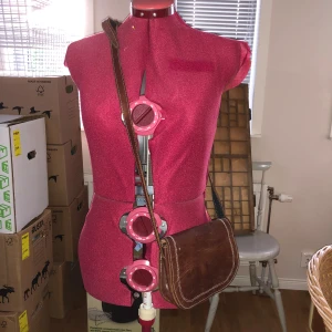 Liten läderväska  - Bra skick. Liten läderväska med två fack som stängs med magnet och en ficka som stängs med dragkedja. Justerbar axelrem