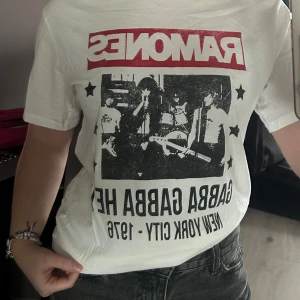 Vit Ramones t-shirt från H&M - Säljer en vit t-shirt från H&M med Ramones-tryck. T-shirten har korta ärmar och ett coolt tryck med texten 'Gabba Gabba Hey' och 'New York City - 1976'. Perfekt för alla Ramones-fans! 🎸