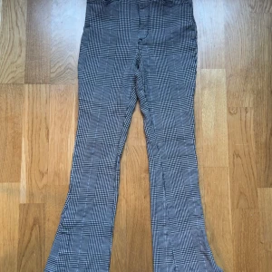 Rutig byxa i svart och vit från H&M (134) - Snygga rutiga byxor i svart och vit med bootcut-stil. Perfekta för en trendig look. Byxorna har en klassisk passform och är tillverkade i ett bekvämt material.