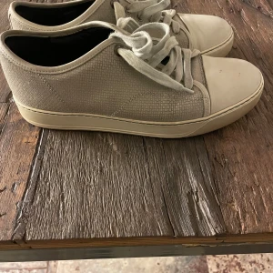 Lanvin skor  - Snygga beige sneakers med snörning och en diskret textur på ovandelen. Skorna har en vit sula och rund tå, vilket ger en stilren look. Perfekta för en avslappnad stil.