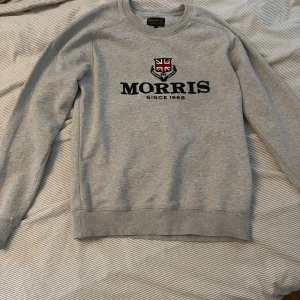 Grå sweatshirt från Morris - Säljer en stilren grå sweatshirt från Morris med broderad logga och Union Jack-märke på bröstet. Riktigt snygg och passar vid alla tillfällen!