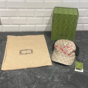 Snygg keps med mönster och ormtryck 🐍 - Otroligt snygg keps med mönster keps och ett iögonfallande ormtryck i rött och vitt. Kepsen har en beige bas och svart mesh på baksidan för ventilation. Bra skick på kepsen 8/10, följer sjävklart med box och påse samt prislapp! Nypris ligger på 3200kr. Perfekt accessoar för att lyfta din stil ✅