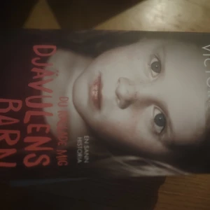 Djävulens barn - Boken 'Djävulens barn' har en omslagsbild av ett barn med en allvarlig blick. Titeln är tryckt i röd text mot en mörk bakgrund. Den verkar handla om en sann historia, vilket framgår av texten på omslaget.