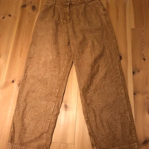 Bruna manchesterbyxor från Cava Company - Snygga bruna manchesterbyxor från Cava Company med en loose passform. Byxorna har en hög midja och en rak stil som ger en avslappnad look. Perfekta för höst och vinter med sitt mjuka och varma material.