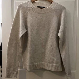 Beige stickad tröja - Säljer en stilren beige stickad tröja från Vero Moda i S. Tröjan har en rund halsringning och långa ärmar med ribbade muddar. Perfekt för kyligare dagar och enkel att matcha med olika outfits. Creamfärgad
