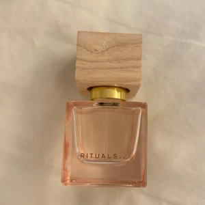 Fleur de Himalaya parfym från Rituals - Elegant parfymflaska från Rituals med doften Fleur de Himalaya. Flaskan är fyrkantig med en ljusrosa ton och har en stilren träkork. Perfekt för den som älskar en sofistikerad och naturlig doft.