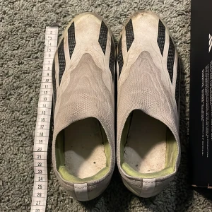 Fotbollsskor från Adidas - (Du får med en sula)Säljer ett par fotbollsskor från Adidas i en stilren design. Skorna är vita med svarta detaljer och har en lime grön sula. De är tillverkade i syntetmaterial och saknar snörning för en smidig passform.Jag kan tvätta dom så skorna ser frächare ut 